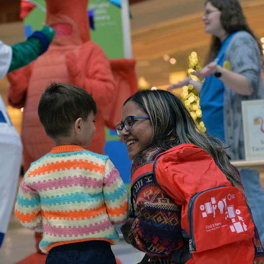 A guardian and child smile at each other while at an OPL event.